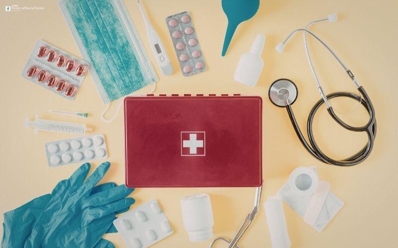 Red first aid kit with medical supplies on a beige background