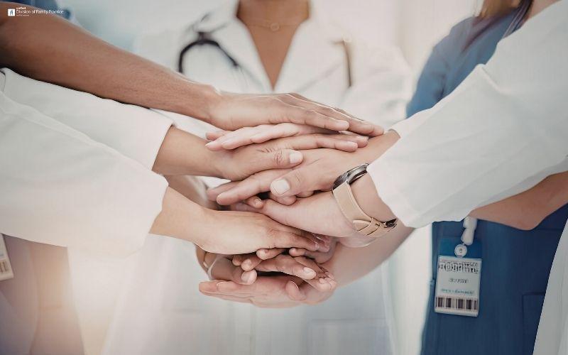 Group of healthcare professionals with their hands stacked together, symbolizing teamwork and collaboration.