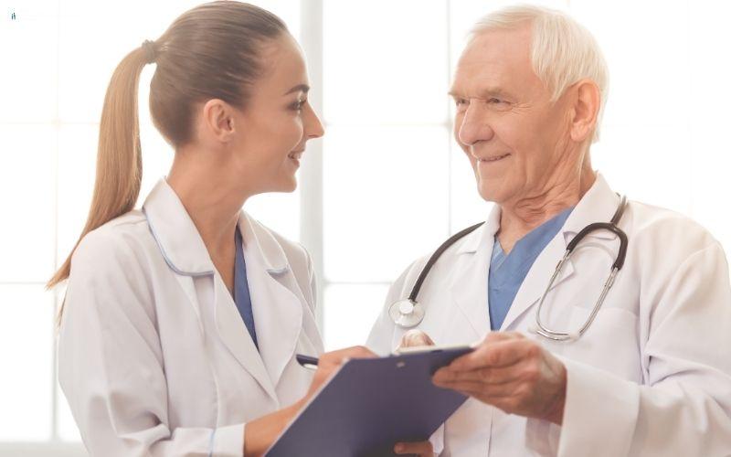 Two doctors in a medical setting, one holding a clipboard and the other with a stethoscope.