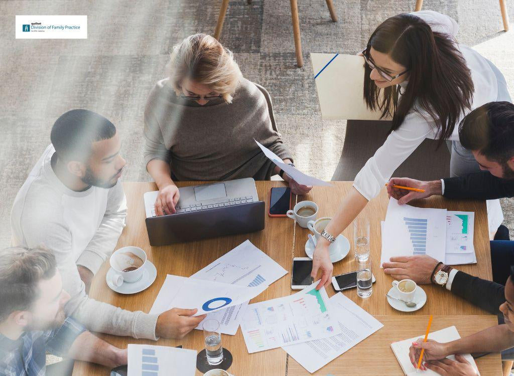 Group of people working together at a table with documents and coffee cups.